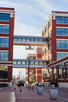 Modern urban renewal at Electric Works, Fort Wayne, Indiana shows vibrant red-brick buildings connected by a pedestrian bridge, symbolizing connectivity and innovation.