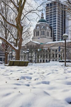 Serenity in Snow: A tranquil morning at Fort Wayne's Freimann Square, capturing the contrast of historic courthouse and modern skyscraper.