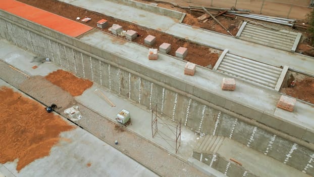 Aerial view of construction site on city embankment. Clip. Process of improving pedestrian road