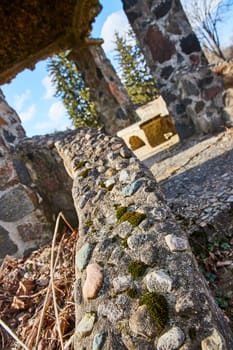 Timeless beauty of war-worn ruins at Lindenwood Cemetery, Indiana, showcasing nature's reclaim in vibrant moss growth on a sunny afternoon.