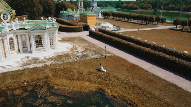 Newlyweds walking in park with historical buildings. Creative. Top view of fabulous walk of newlyweds in estate on summer day. Beautiful territory of old estate with garden.