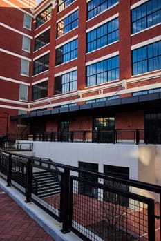 Electric Works' modern architectural masterpiece in Fort Wayne, Indiana, showcasing a blend of old and new with red bricks and reflective glass windows against a clear sky.