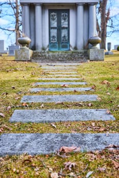 Somber and serene view of weathered stone steps leading to a historic mausoleum at Lindenwood Cemetery, Fort Wayne, embodying timeless tranquility.