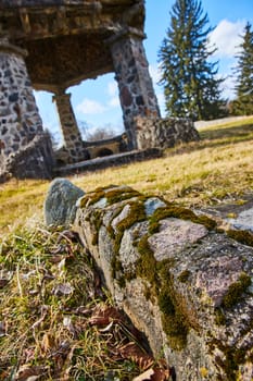 Moss-covered stones lead to historic ruins under a sunny sky in Lindenwood Cemetery, Fort Wayne, capturing nature's reclamation of architecture.