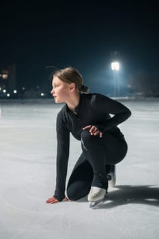 Beautiful young woman ice skating and performing she program over city outdoor ice arena. Winter activities concept