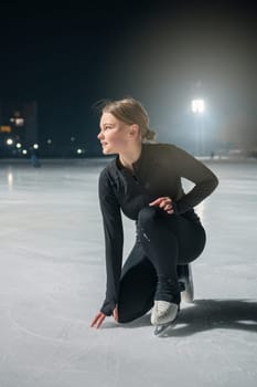 Beautiful young woman ice skating and performing she program over city outdoor ice arena. Winter activities concept