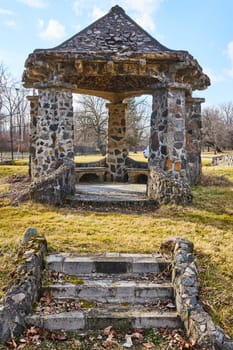 Rustic stone gazebo bathed in daylight at Lindenwood Cemetery, Fort Wayne, Indiana, a symbol of tranquility and timeless beauty.