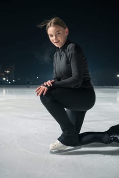 Beautiful young woman ice skating and performing she program over city outdoor ice arena. Winter activities concept