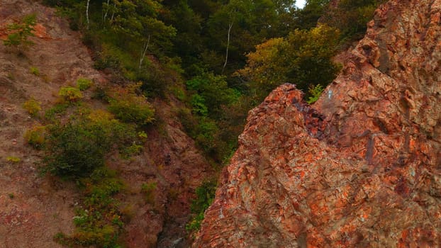 Top view of rocky ridge with forest gorge. CLip. Amazing nature with rocky slopes of green gorge. Cinematic rocks with green trees in gorge.