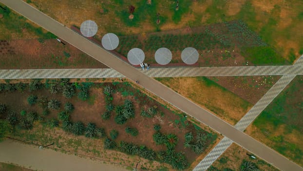 Top view of people walking in park alley in city. Clip. People walk and relax in modern city park. Landscape of city park alley with solar panels.