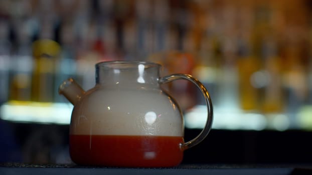 Close up of making red fruit tea at a bar or restaurant. Media. Bartender adding smoke into the tea pot through the tube