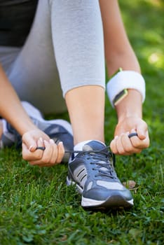 Sneakers, hands and tie shoelace in park, ready for run or cardio for fitness and sports outdoor. Exercise, workout and person with shoes on grass for training, health and wellness with runner.