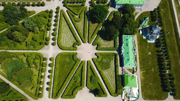 Top view of royal garden with patterns and ancient buildings. Creative. Amazing beauty of garden pattern and trails of royal palace. Territory of old rich estate with garden on sunny summer day.