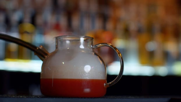 Close up of making red fruit tea at a bar or restaurant. Media. Bartender adding smoke into the tea pot through the tube