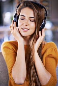 Woman, headphones and listening to audio on couch, relax and streaming radio for music or sound. Female person, home and chill on sofa for peace, comfortable and hearing jazz playlist on weekend.