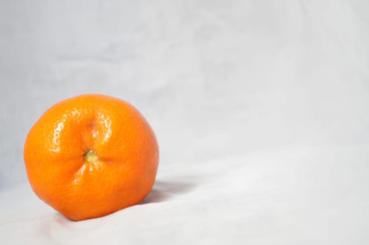 A small orange sits on a white background. High quality photo