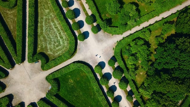 Top view of people walking on geometric garden paths. Creative. Beautiful patterns of palace garden on sunny summer day. Territory of palace garden with beautiful paths and labyrinths.