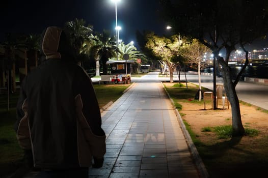 A man is walking down a sidewalk at night. High quality photo