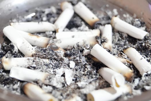 A pile of burnt cigarette butts in a pan. High quality photo