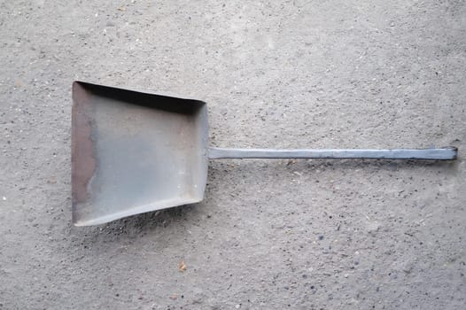 A metal spatula is laying on a grey surface. High quality photo