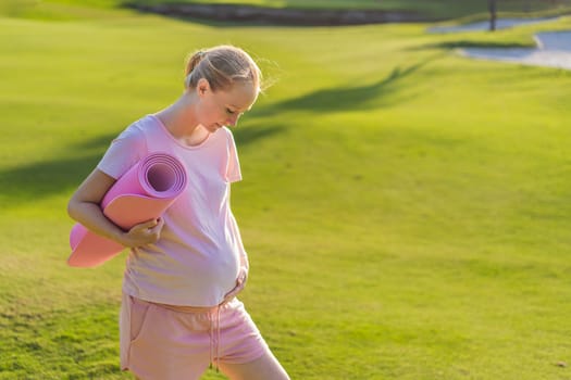 Energetic pregnant woman takes her workout outdoors, using an exercise mat for a refreshing and health-conscious outdoor exercise session.