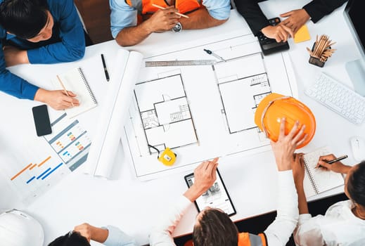 Top view banner of diverse group of civil engineer and client working together on architectural project, reviewing construction plan and building blueprint at meeting table. Prudent