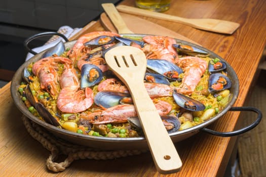 Seafood paella ready to be served with a wooden spatula on the table, typical Spanish cuisine, Majorca, Balearic Islands, Spain,