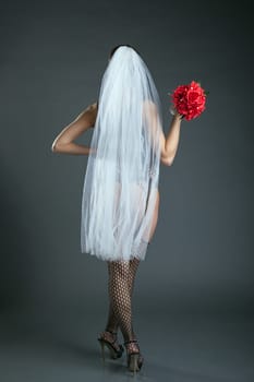 Slender model posing in veil and black stockings, on gray background