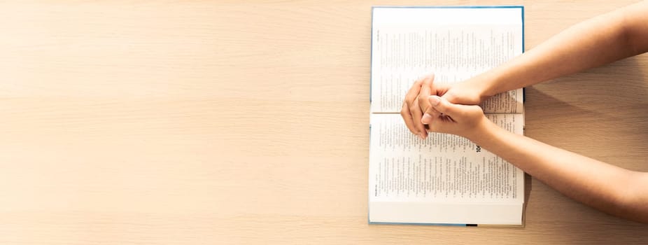 Female prayer folding hand on holy bible book on wooden church table. Concept of hope, religion, faith, christianity praying for love and god blessing. Warm and brown background.Top view. Burgeoning.