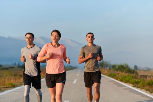 A group of friends, athletes, and joggers embrace the early morning hours as they run through the misty dawn, energized by the rising sun and surrounded by the tranquil beauty of nature.