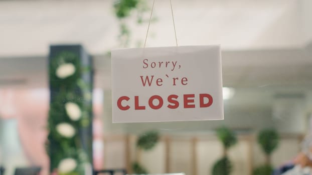 Sorry we are closed sign in empty fancy fashion boutique with stylish formal clothes. Message on designer clothing men premium showroom door announcing customers that shop is closed