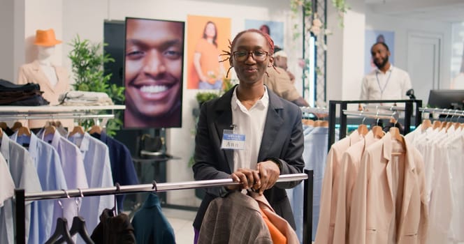 Portrait of employee arranging clothes in mall clothing store with fast fashion attire following the latest trends. Worker organizing assortment of elegant men blazers in modern clean fashion boutique