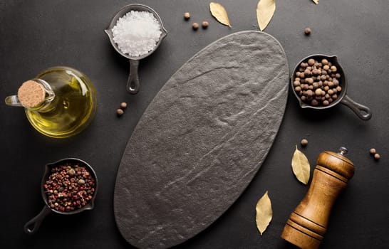 Various spices and an empty black board on the table. Salt, pepper and olive oil, top view