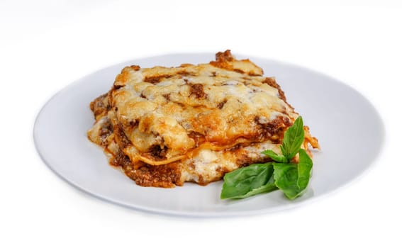 slice of lasagna with melted cheese on top and minced meat filling close-up isolated on white background with shadow