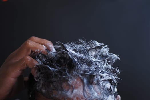 young men washes h his hair with shampoo