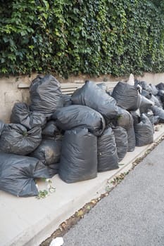 Black garbage bags stack on a park .