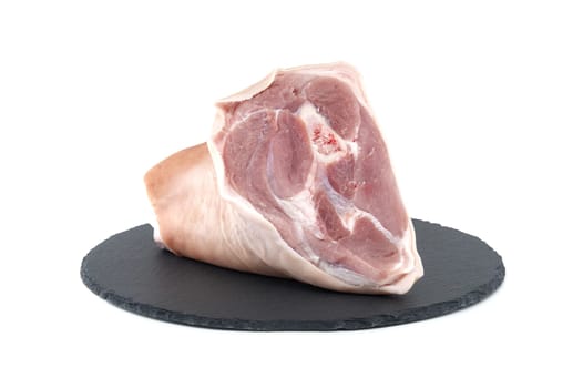 Fresh raw pork shank on black stone plate over white background