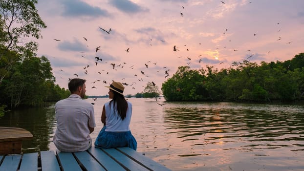 Sea Eagles at sunset in the mangrove of Chantaburi in Thailand, couple of men and women watching the sunset on a wooden pier