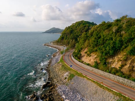 car driving on the curved road alongside the ocean beach road of Thailand. road landscape in summer. it's nice to drive on the beachside highway. Chantaburi Province Thailand, drone view