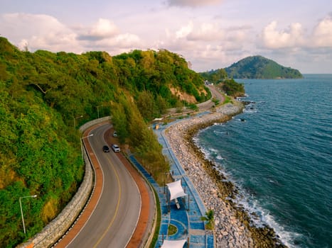 drone view at a car driving on the curved road alongside the ocean beach road of Thailand. road landscape in summer. it's nice to drive on the beachside highway. Chantaburi Province Thailand,