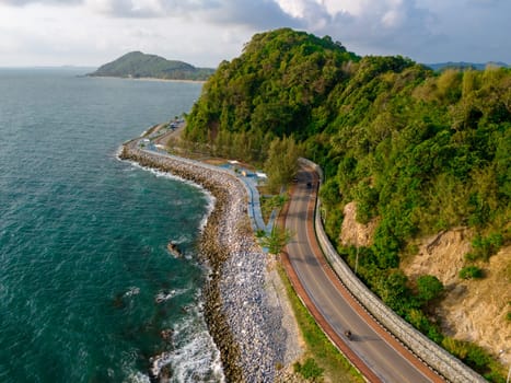 top view of a car driving on the curved road alongside the ocean beach road of Thailand. road landscape in summer. it's nice to drive on the beachside highway. Chantaburi Province Thailand,