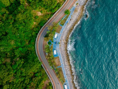 car driving on the curved road alongside the ocean beach road, top view at a road landscape in summer. it's nice to drive on the beachside highway. Chantaburi Province Thailand,