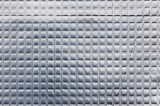 Full-frame texture of aluminum coated butil rubber sheet with square pattern. This material is used for sound dampening in car interiors and vibration resonance reducing and acoustic improving.