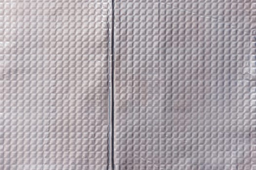 Full-frame texture of aluminum coated butil rubber sheet with square pattern. This material is used for sound dampening in car interiors and vibration resonance reducing and acoustic improving.