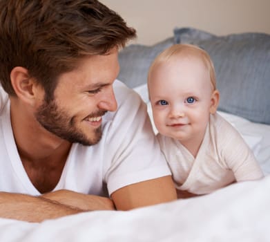 Happy, sweet and baby with father on bed relaxing, playing and bonding together at home. Smile, love and young dad laying with girl child, infant or kid in bedroom or nursery at family house