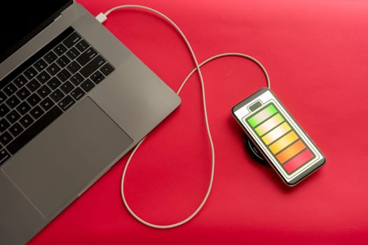 Mobile phone on red desk office charge with computer. - image