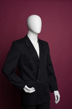 White male mannequin in a black business suit on a ruby background - image