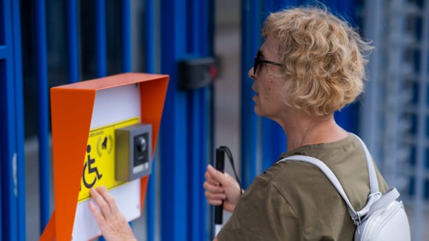 An elderly blind woman reading a text in braille. Button for calling help for people with disabilities