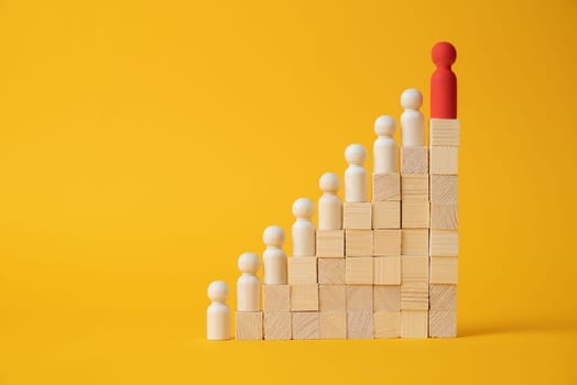 The concept of career growth. Wooden figurines stand on a ladder made wooden block on a yellow background.