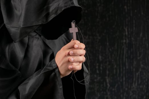 A monk praying with a rosary and crucifix in his hand.